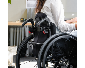 Close up back view of manual wheelchair with person sitting in it slightly tilted to the left.
