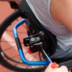 Close up image of a blue backrest on a wheelchair whilst someone sits in it.