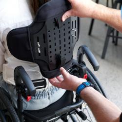 Back view of a Zygo back support with human hand showing how to adjust it.