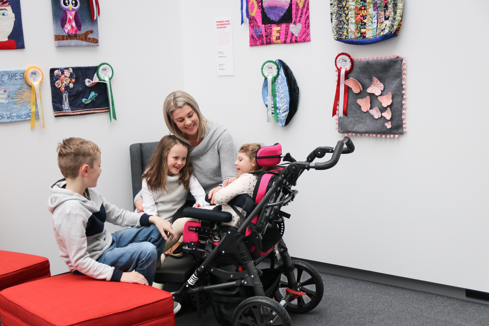 A happy family looking at a happy child in a Ella Wonderseat with Black Wheels
